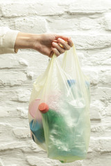Woman holding a plastic bag full of single-use plastic waste