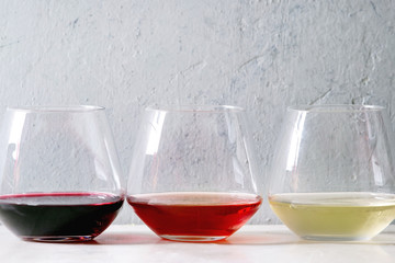 Variety of wine. Red, rose and white wine in old fashion glasses in row on white marble table. Copy space