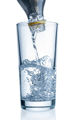 Flowing pure water from bottle into glass on white background