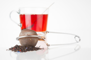 Tea strainer and tea cup on white background
