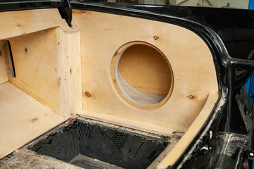 Luggage compartment of a black car sedan with a box made of wood and sawn holes for the...