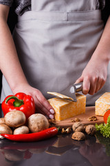 young woman slicing cheese in a gray apron