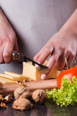 young woman slicing cheese in a gray apron