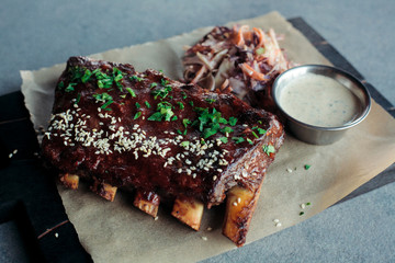 grilled ribs with spices sesame and greens decorated with garlic sauce and salad