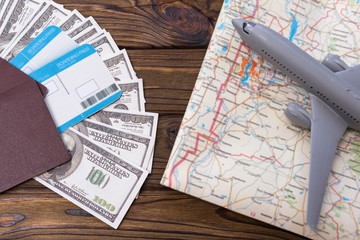 Passports, tickets, us dollar bills, plane, geographical map on the background of a wooden table. Travel, tourism.
