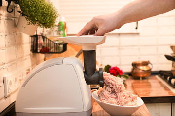 cooking minced meat in an electric meat grinder on the kitchen table