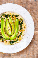 Pasta with avocado on wooden table