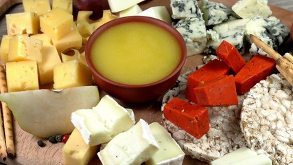 Cheese plate close-up with several varieties of fruit and honey cheese.