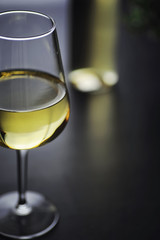 Transparent bottle of white dry wine on the table. White wine glass on a wooden background.