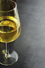 Transparent bottle of white dry wine on the table. White wine glass on a wooden background.