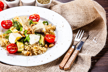 Salad with avocado and cheese on wooden background