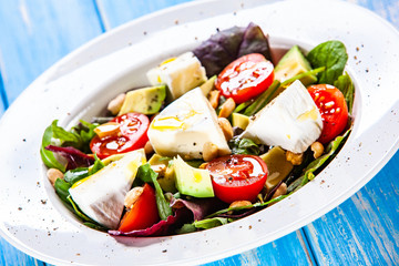 Salad with avocado and cheese on wooden background