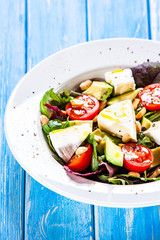 Salad with avocado and cheese on wooden background