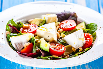 Salad with avocado and cheese on wooden background
