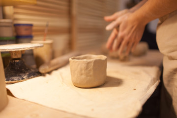 Female potter works with ceramic at his workshop. Young woman work inside 