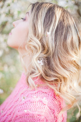 Spring portrait of a young blonde near a flowering tree. Happy young woman.