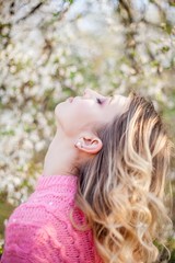 Spring portrait of a young blonde near a flowering tree. Happy young woman.