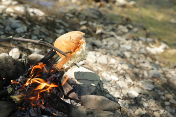 Bonfire near the river in a hike, fry bread on a fire near the river.