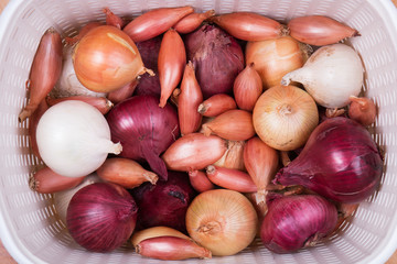Onions of different varieties in a white basket. Top view