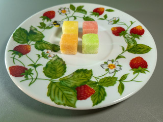 Colored fruit sugar cubes on a plate. Fruit sugar.