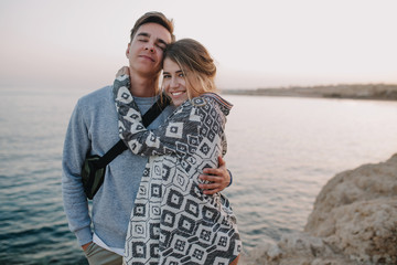 Charming long-haired girl posing with her stylish boyfriend in trendy hat, gently touching his...