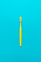 minimalist flat lay photo of yellow toothbrush over turquoise blue background