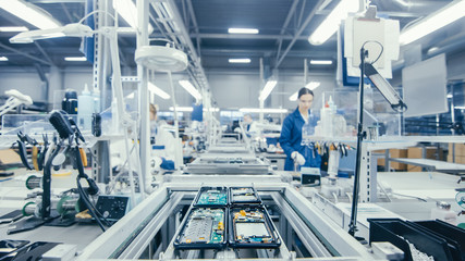 Fototapeta Shot of an Electronics Factory Workers Assembling Circuit Boards by Hand While it Stands on the Assembly Line. High Tech Factory Facility. obraz