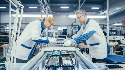 Shot of an Electronics Factory Workers Assembling Circuit Boards by Hand While it Stands on the...