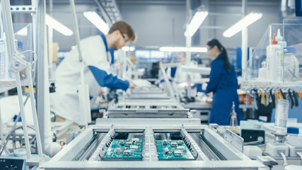 Shot of an Electronics Factory Workers Assembling Circuit Boards by Hand While it Stands on the...
