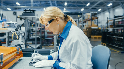 Senior Electronics Factory Worker in White Work Coats Inserting Microchips, Processors and...