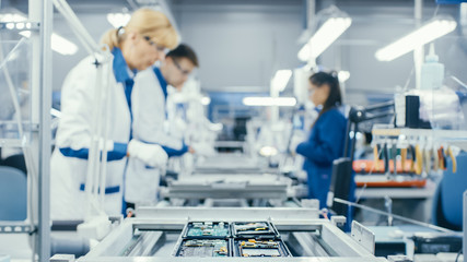 Shot of an Electronics Factory Workers Assembling Circuit Boards by Hand While it Moves on the...
