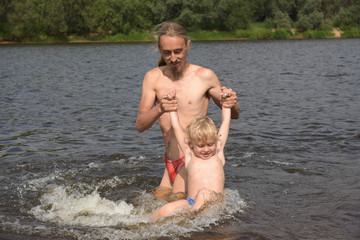 father teaching his little son to swim, they are happy. swimming season, summer, fun holiday by the river.