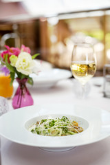 Fresh salad in restaurant with white wine and flowers on the table