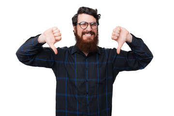 A bearded nerd, showing a dislike gesture with thumbs down over white background
