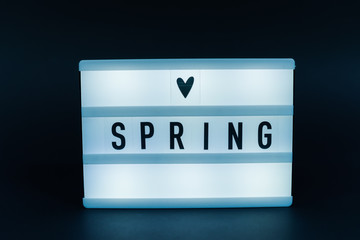 Photo of a light box with text, SPRING, dark background