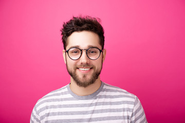 Obraz premium Portrait of handsome smiling man with glasses, over pink isolated background