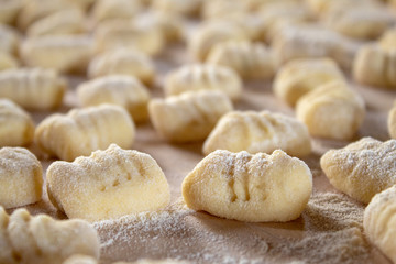 Italian food speciality: hand made potato gnocchi on a wooden board, ready to be cooked. Home made and hand rolled on a fork. Close up, selective focus.
