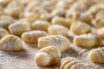 Italian food speciality: hand made potato gnocchi on a wooden board, ready to be cooked. Home made and hand rolled on a fork. Close up, selective focus.