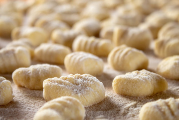 Italian food speciality: hand made potato gnocchi on a wooden board, ready to be cooked. Home made and hand rolled on a fork. Close up, selective focus.