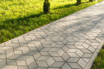 The footpath in the park is paved with diamond shaped concrete tiles.