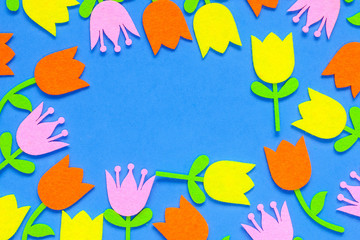 Fototapeta na wymiar Felt tulip flower cutouts of pink, yellow and orange on a blue background