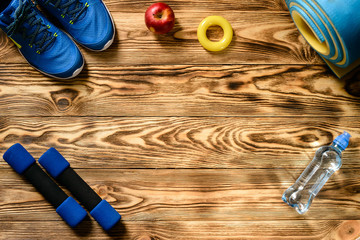 wooden background with place for text, sports dumbbells, sneakers and a bottle of water