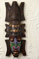 Ashanti carved wood ceremonial mask from Ghana with beads and brass on stucco wall