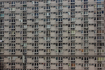 white plastic windows of an apartment building, symmetrical frames in a gray house. many rooms in one house. modern housing construction. old building
