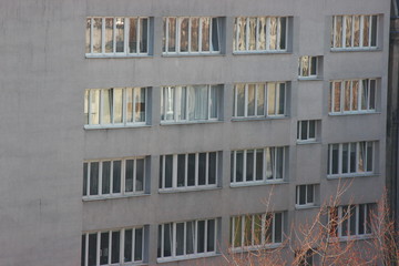 Fototapeta na wymiar white plastic windows of an apartment building, symmetrical frames in a gray house. many rooms in one house. modern housing construction. old building