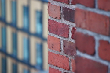 the red brick wall contrasts with the modern buildings of glass, concrete and steel. wall of an old...