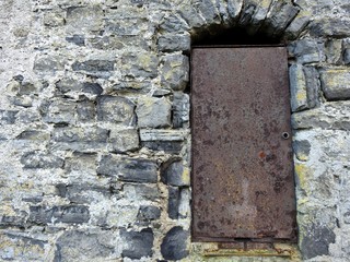 Old metal door surrounded by stone wall.