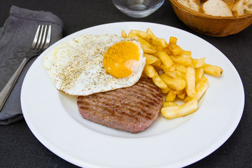 steak haché de boeuf, oeuf et frites dans une assiette