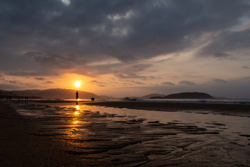 Fototapeta premium Silhouettes of people on the background of a golden dawn on the beach of Sanya, Hainan Island, China