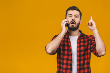 Young stylish hipster guy in casual, holds smart phone, raises index finger, quotes someone words, proves his rightness. People and technology concept.